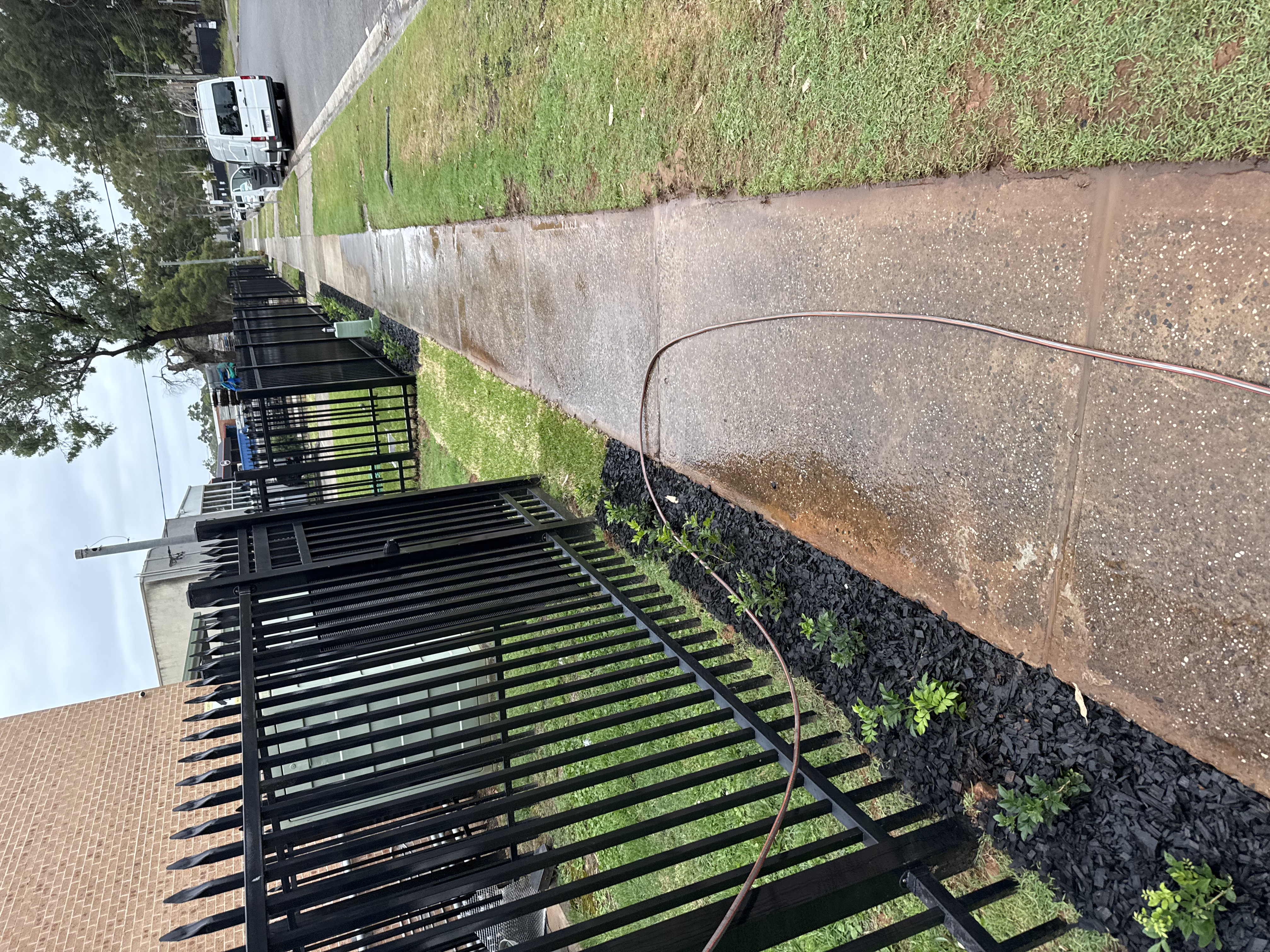 Mulched garden bed along fence line beside footpath
